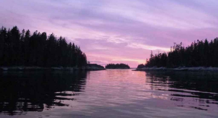 purple skies reflect off still water in maine